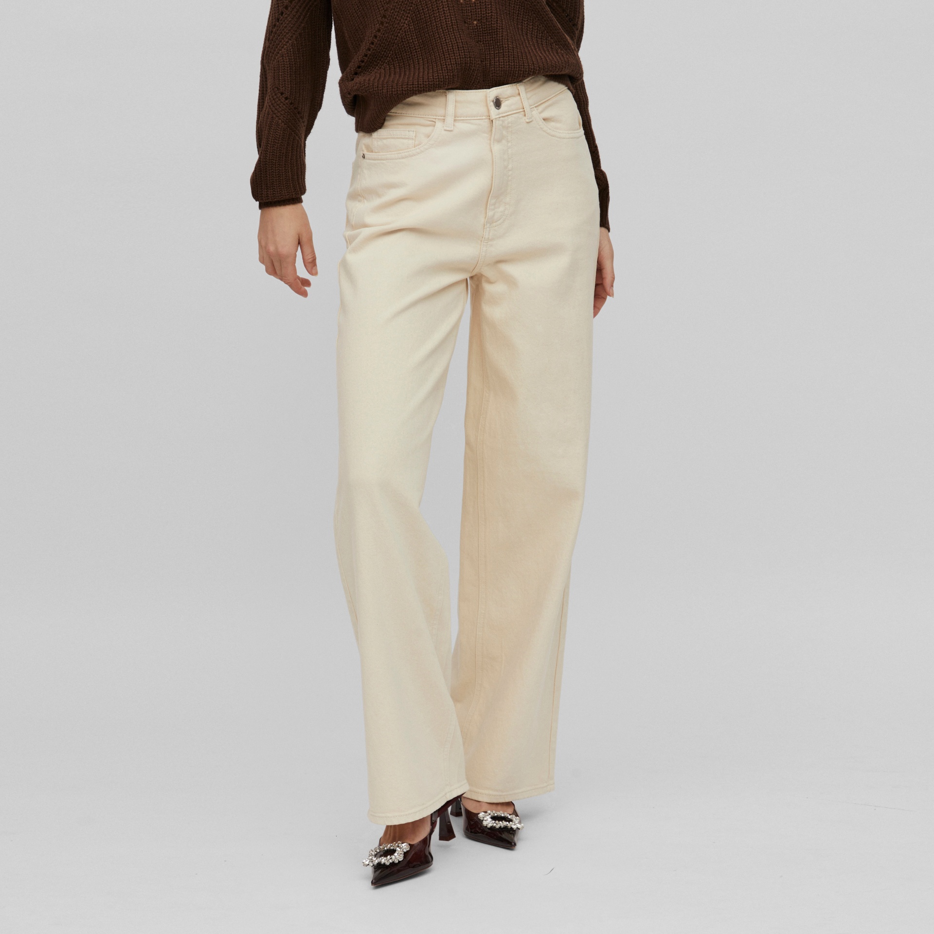 Calças bege retas usadas com camisola castanha e sapatos pretos