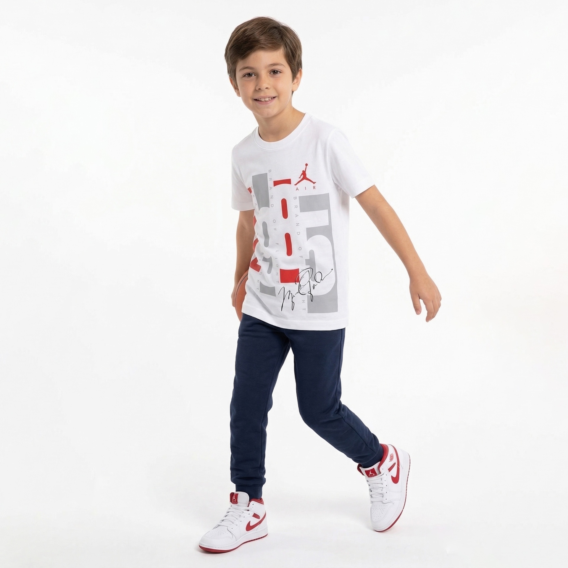 Camisola branca com estampado em vermelho e cinzento, calças azul escuro e sapatilhas brancas e vermelhas para criança