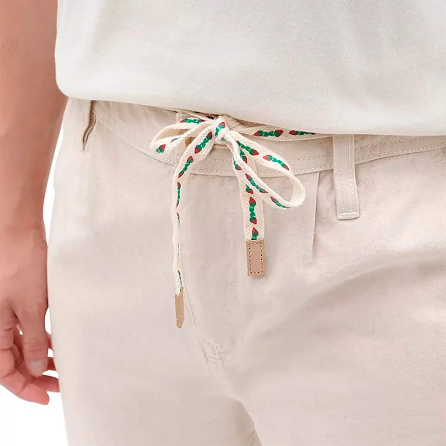 Calças bege claro com cordão branco com padrão verde e vermelho na cintura