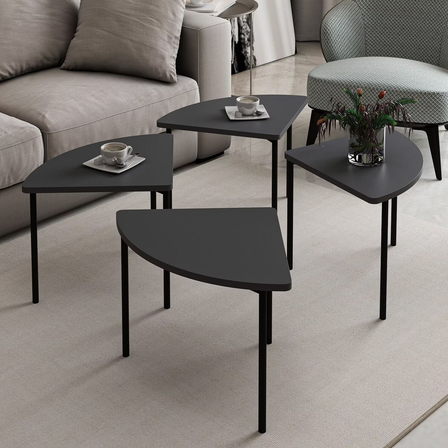 Conjunto de mesas laterais negras triangulares com pernas metálicas finas em sala com sofá e poltrona.