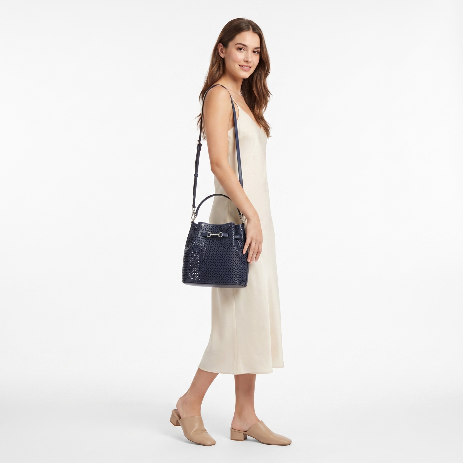 Mulher com vestido creme e mala azul escura com padrão recortado