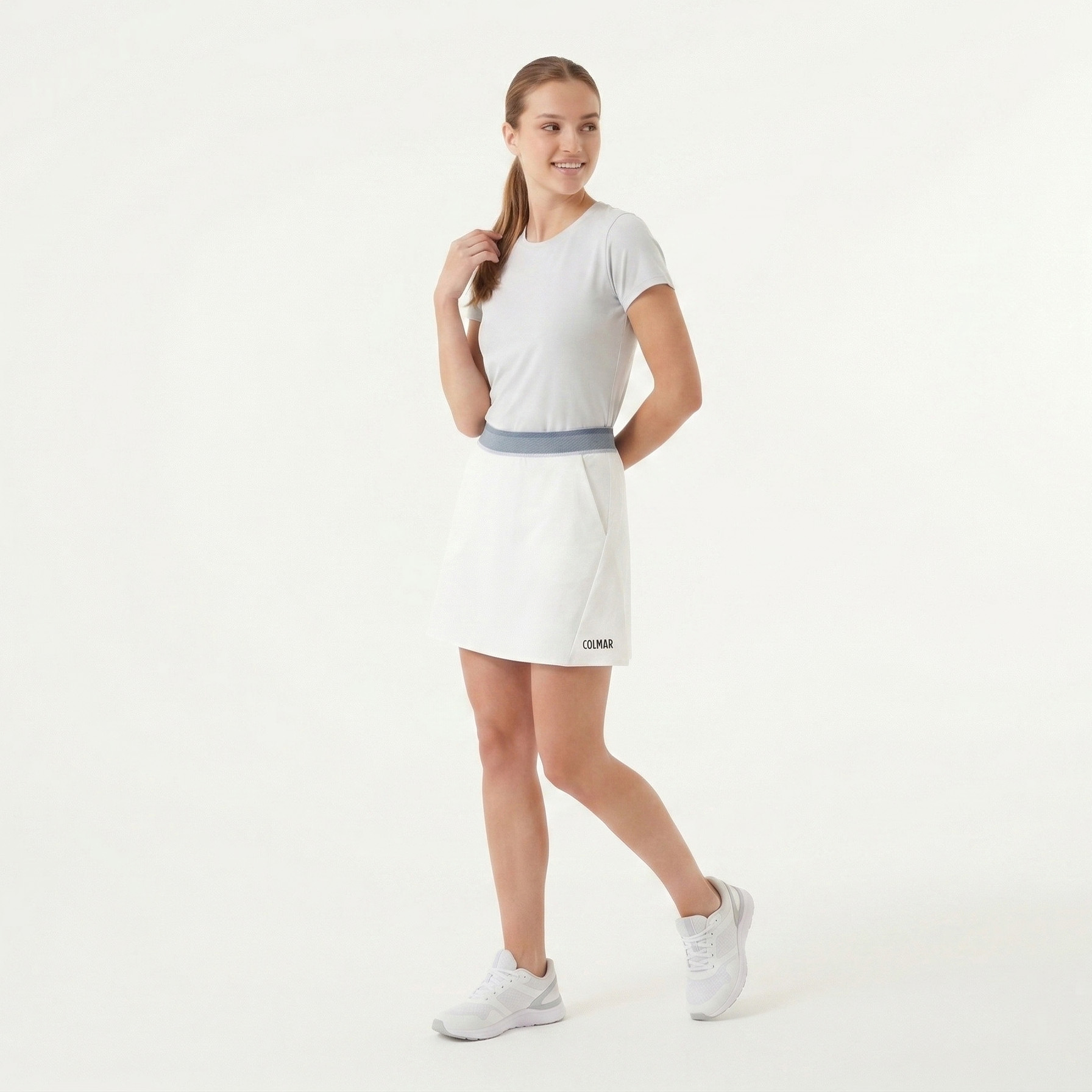 Mulher com saia branca COLMAR e camisola branca em fundo branco