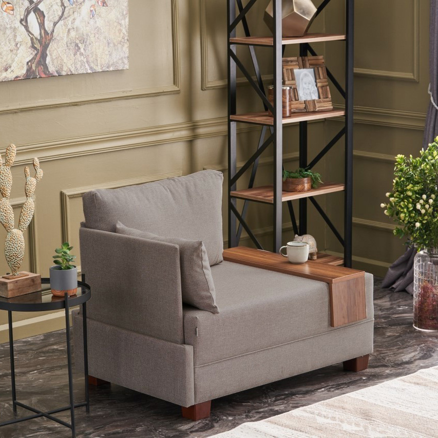 Poltrona cinza com estrutura em madeira castanho e almofadas, numa sala com mesa preta, plantas e estante de madeira e metal preto.