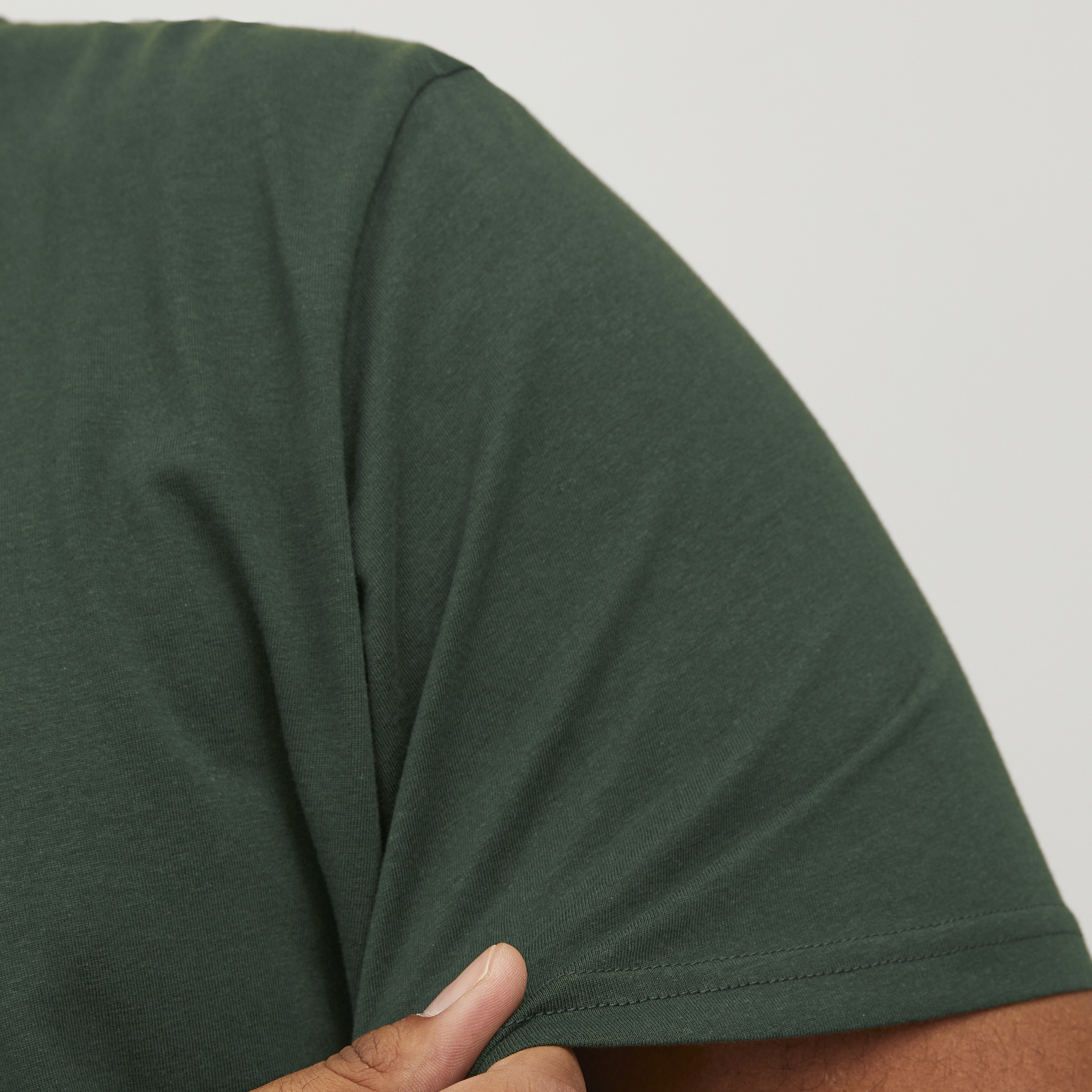 Camiseta verde escura de manga curta com mão a puxar a manga