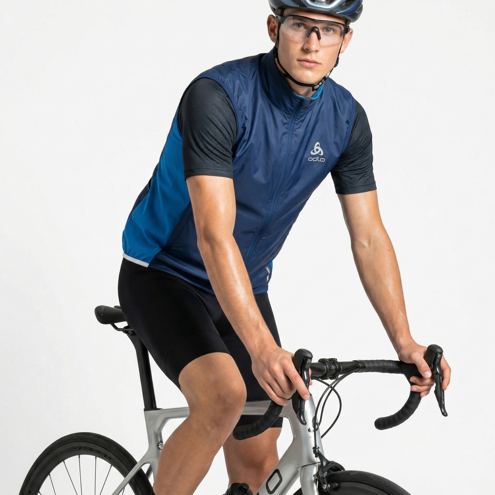 Homem a pedalar bicicleta de estrada com colete azul Odlo e capacete azul