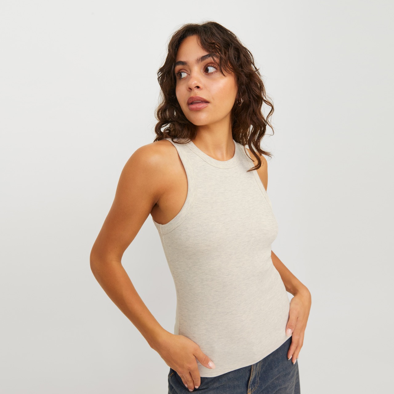 Top feminino bege claro sem mangas com calças jeans azuis