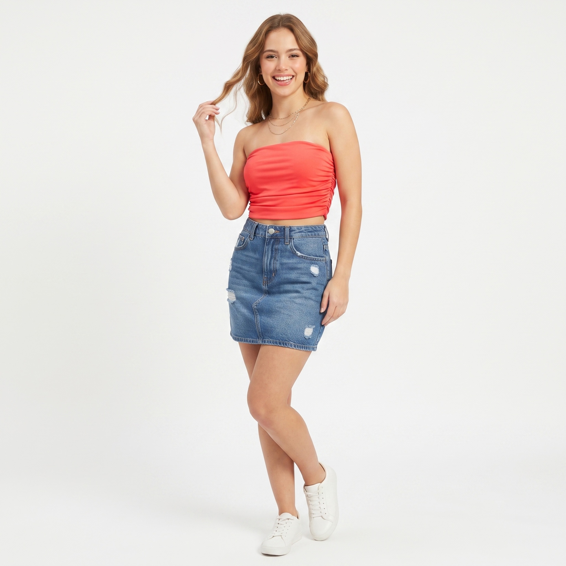 Mulher a usar top bandeau vermelho, saia jeans curta azul clara e ténis brancos