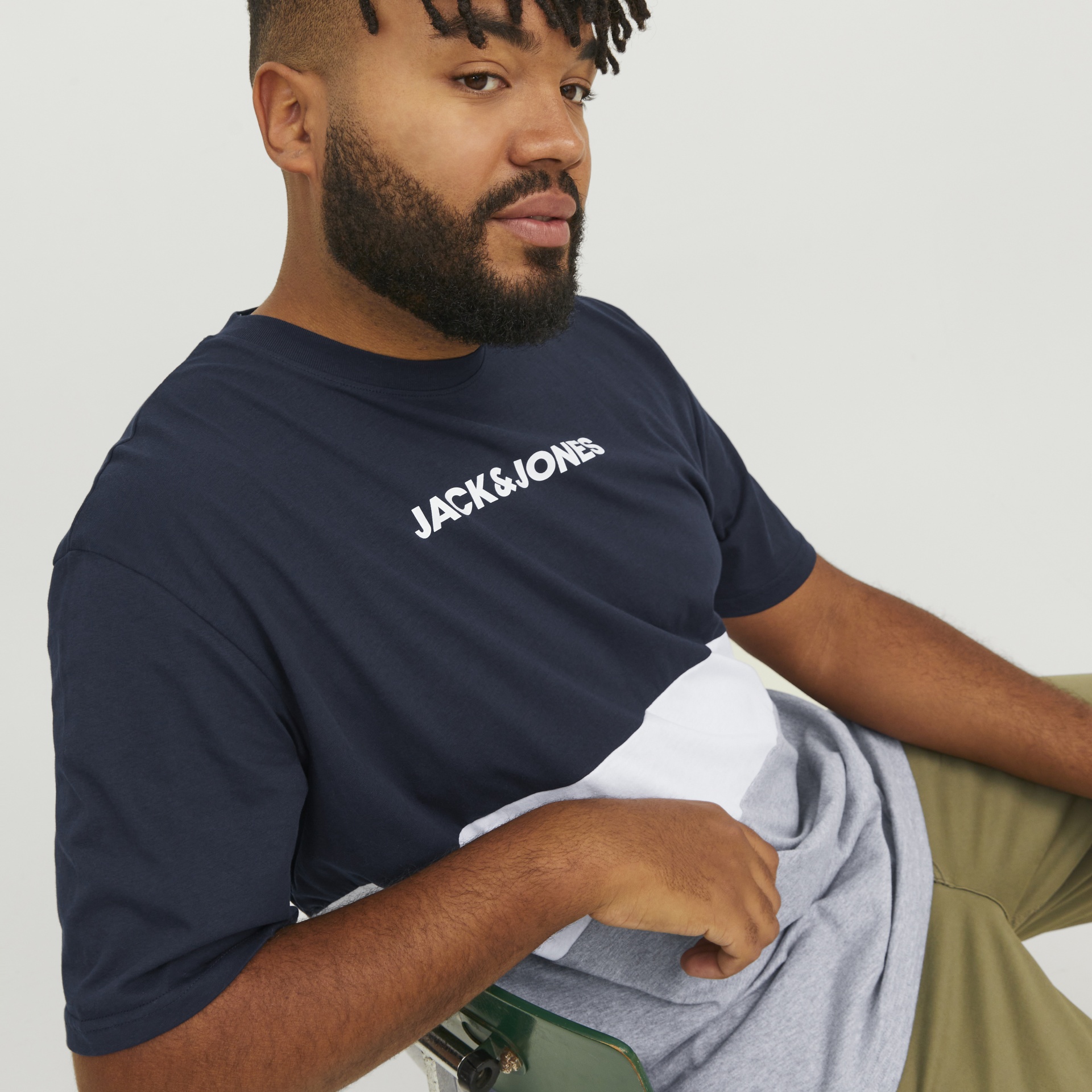 Homem a usar t-shirt tricolor azul escuro, branco e cinzento com texto JACK & JONES