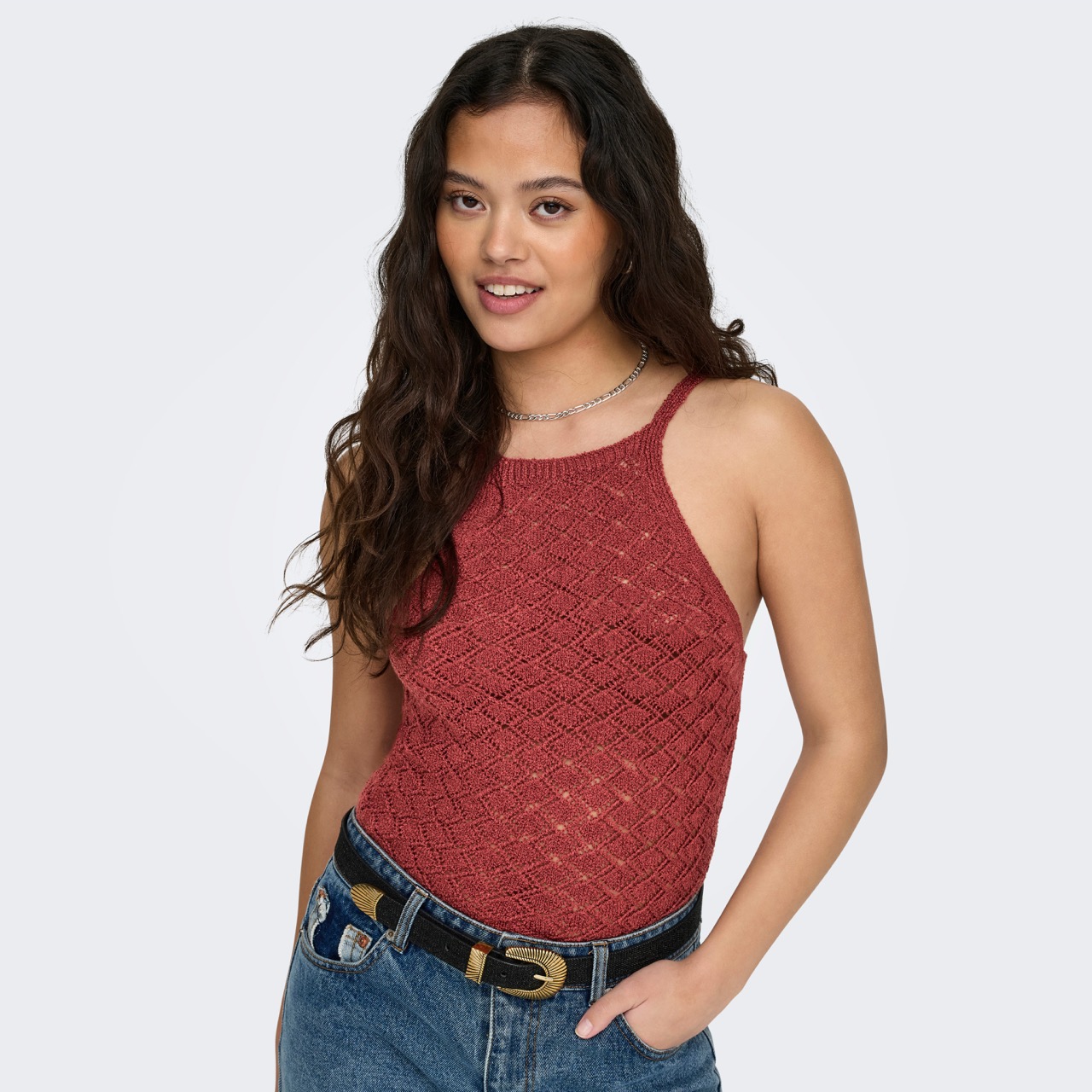 Top feminino vermelho em malha com padrão geométrico, calças jeans azuis e cinto preto
