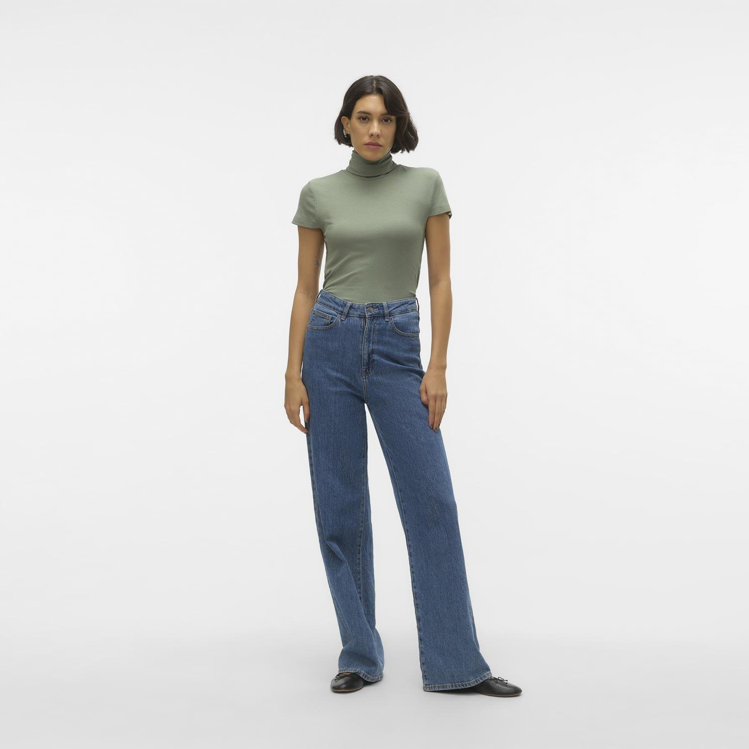 Mulher com calças de ganga azul claro e t-shirt verde-oliva em fundo branco