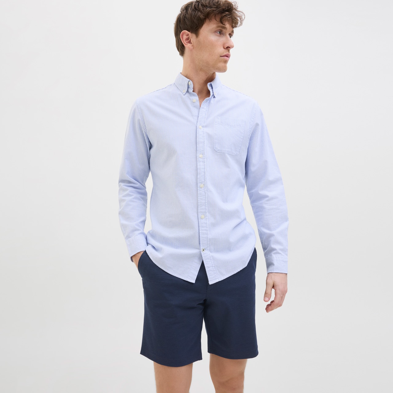 Homem com camisa azul clara de manga comprida e calções azuis escuros