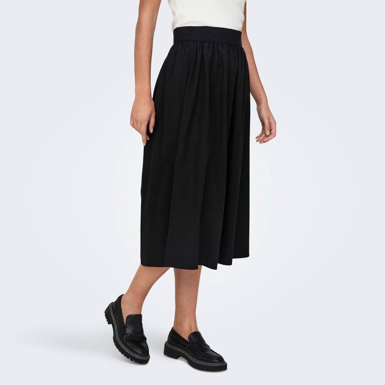 Saia midi preta com cintura elástica, pregas, usada com sapatos pretos e top branco