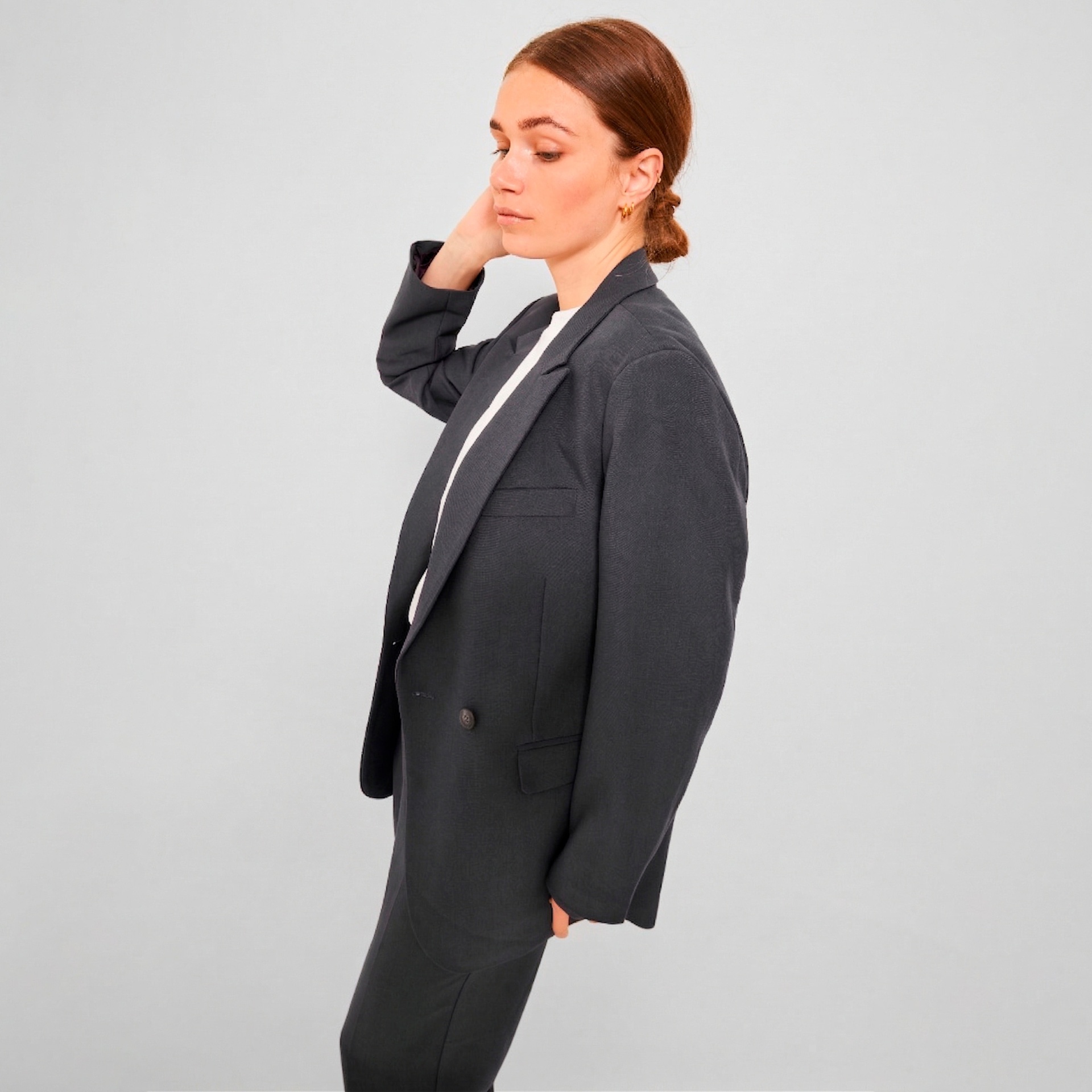 Mulher a vestir blazer cinza escuro com t-shirt branca e calças cinza escuro