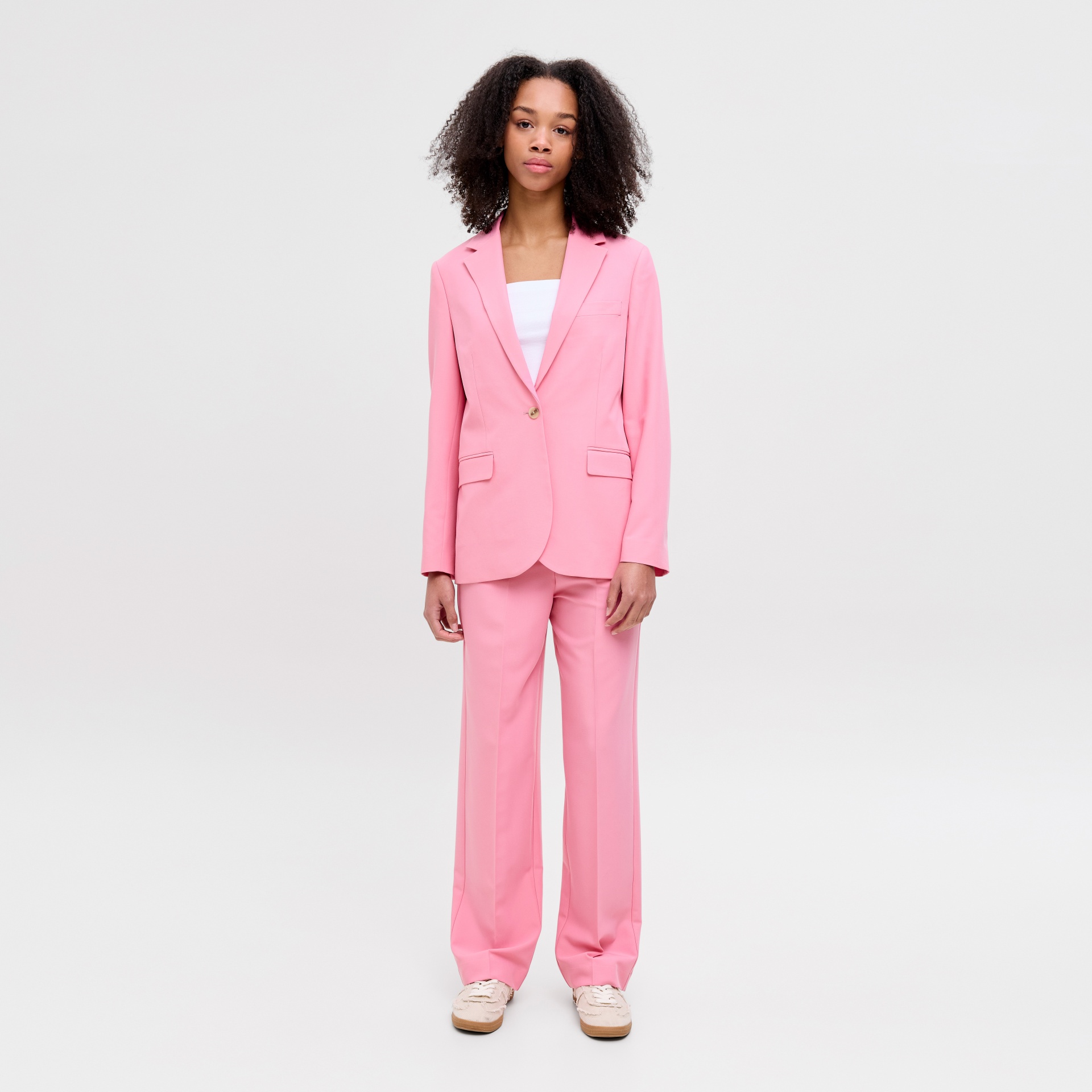 Conjunto feit de fato feminino rosa com blazer e calças largas em modelo com ténis bege