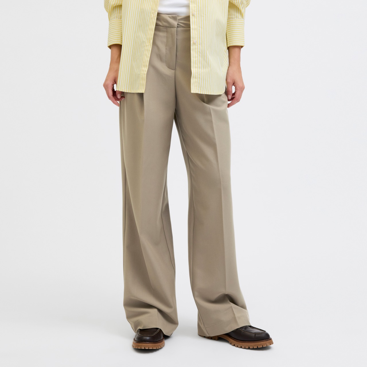 Calças largas bege com camisa amarela clara e sapatos castanhos