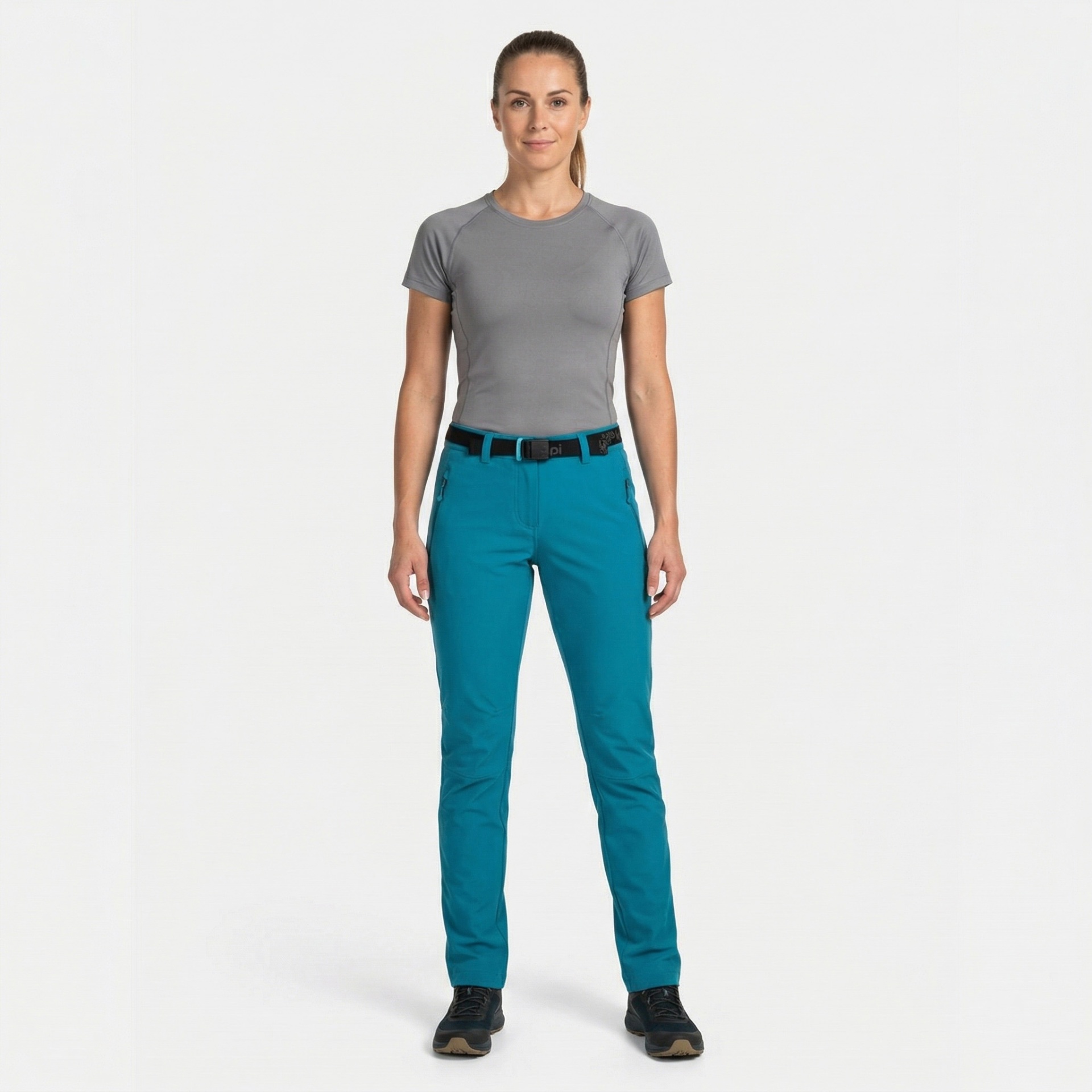 Mulher com t-shirt cinza e calças azuis com cinto preto, fundo branco