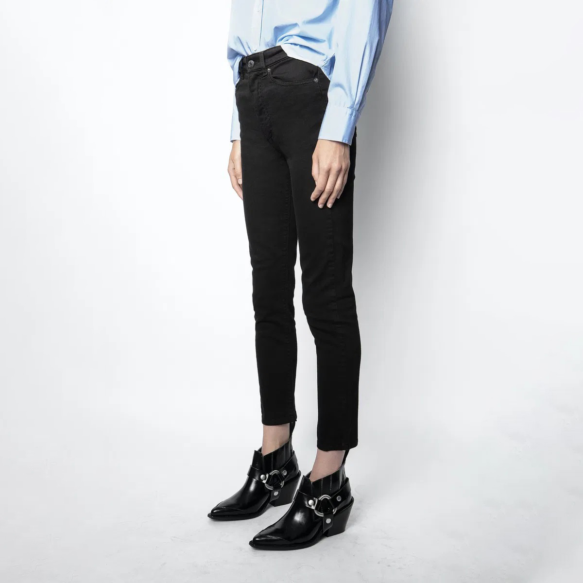 Calças pretas justas com botins pretos e camisa azul clara
