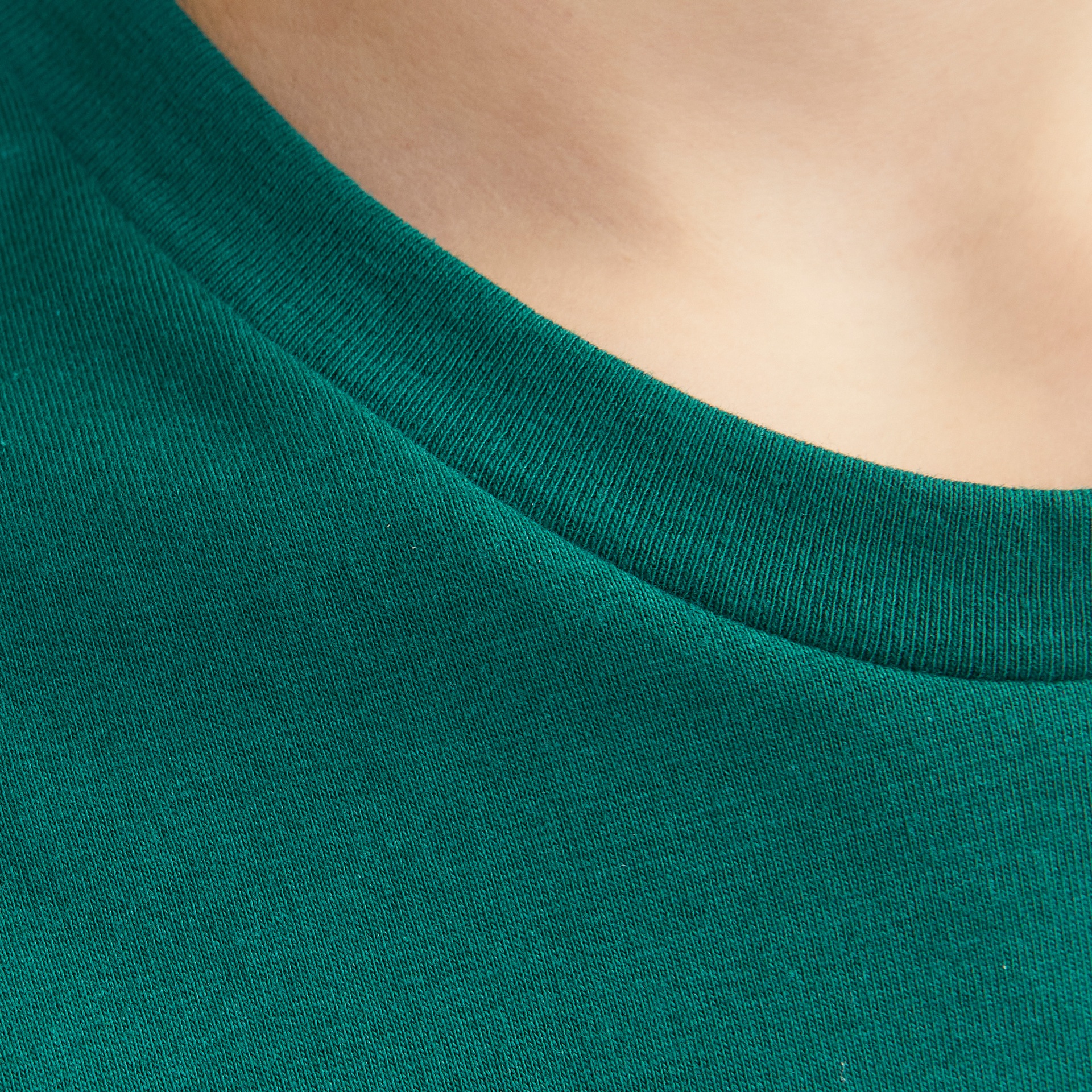 Close-up do decote redondo de uma t-shirt verde de malha fina