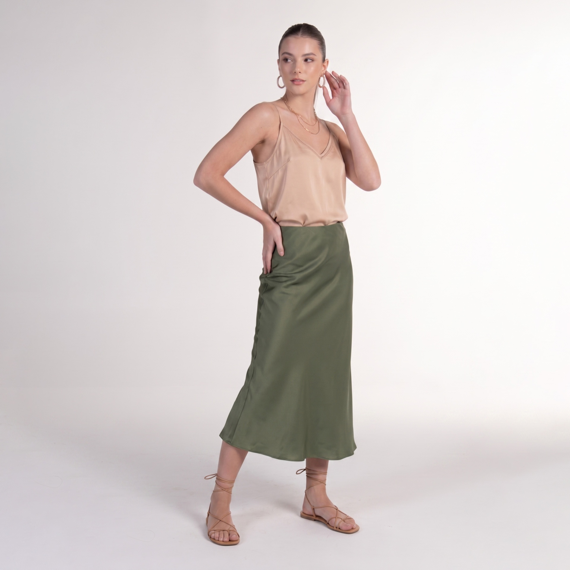 Mulher com regata bege, saia midi verde e sandálias nude