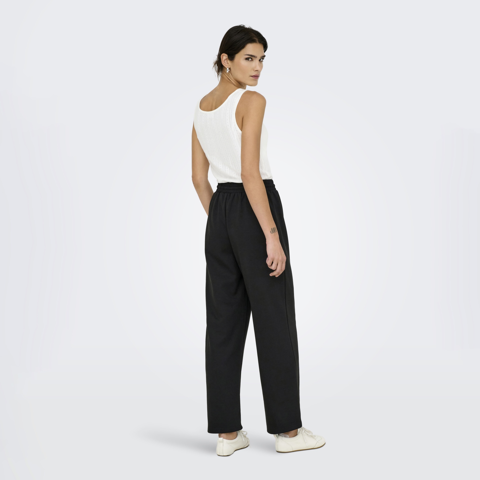 Mulher de costas com camisola branca e calças pretas