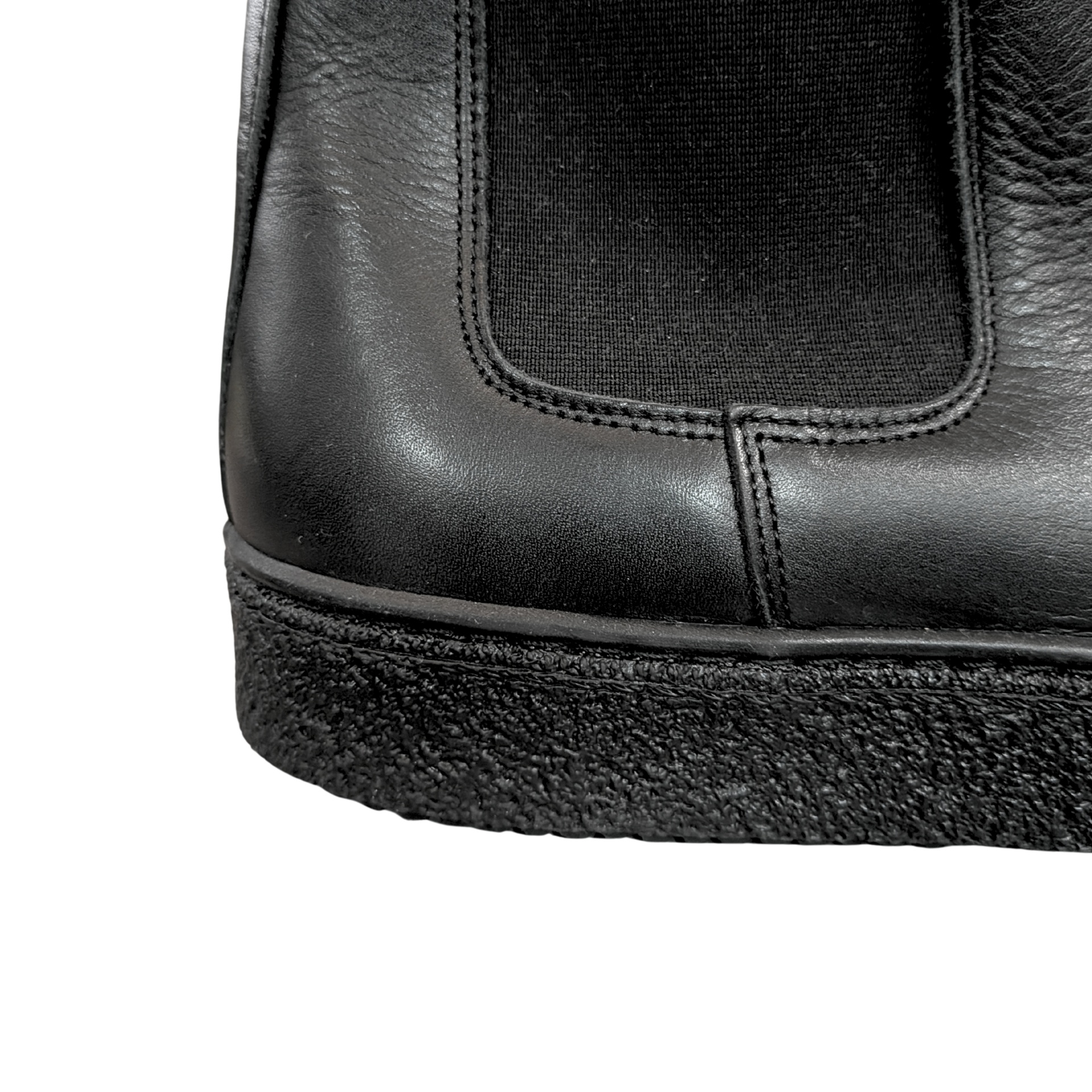 Detalhe de bota preta em pele e tecido com sola texturada preta