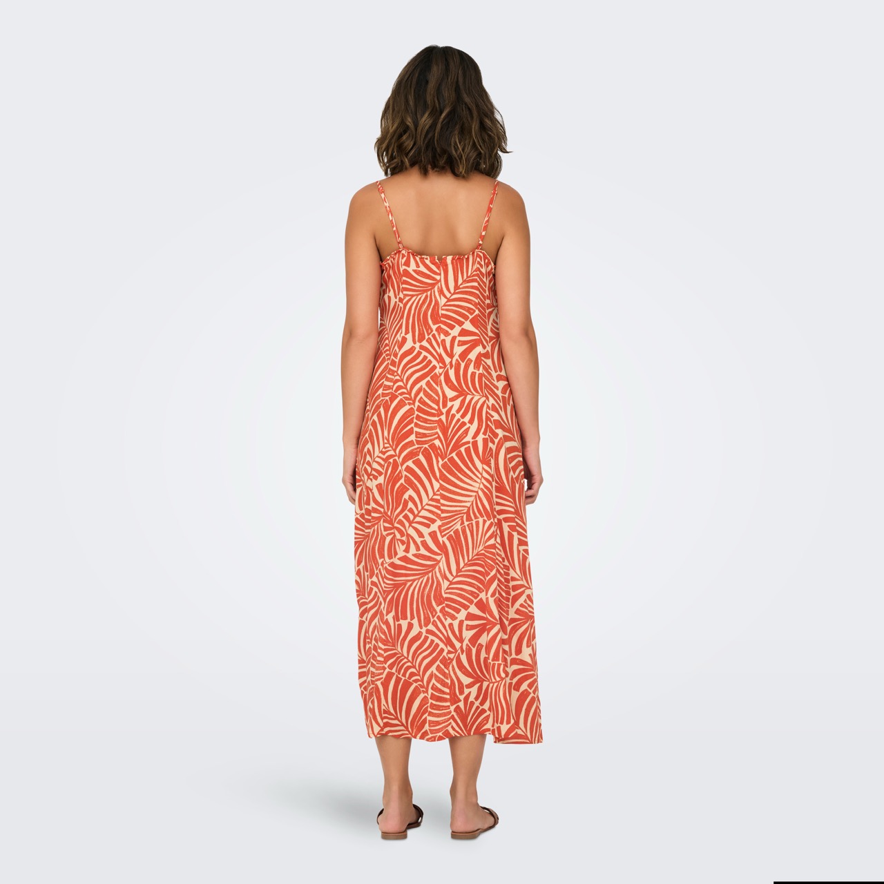 Vestido comprido laranja com padrão de folhas brancas visto de costas