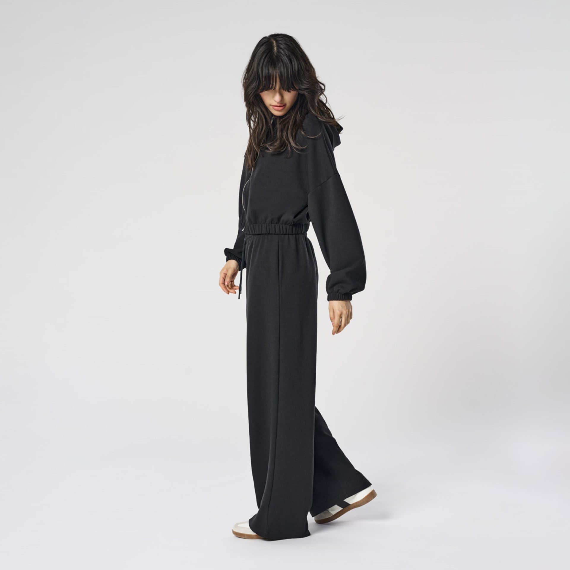 Mulher com roupa preta de mangas compridas e calças largas