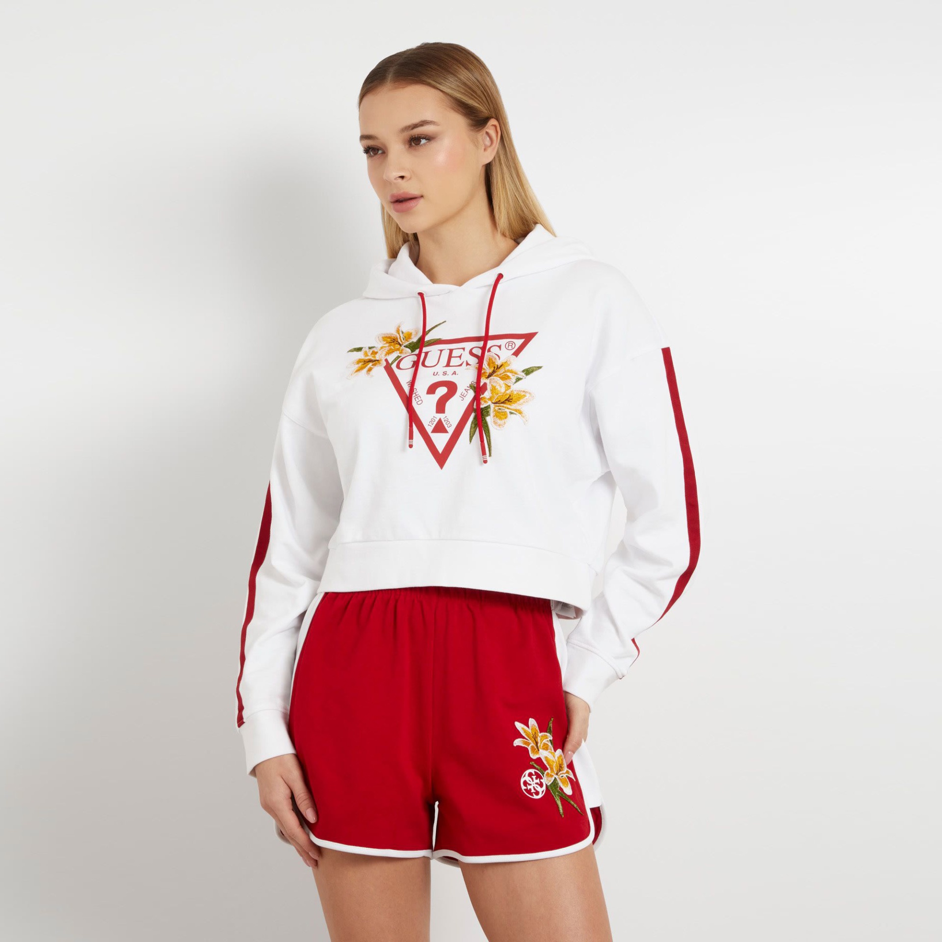 Sweatshirt branca com cordões vermelhos e logótipo Guess com flores, com calções vermelhos bordados.