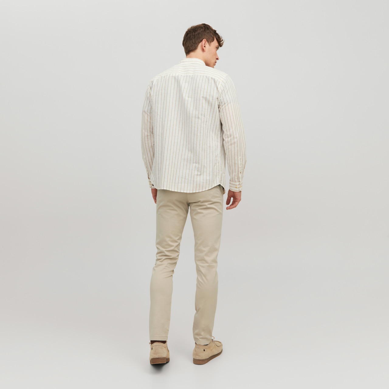 Homem de costas com camisa riscada e calças bege