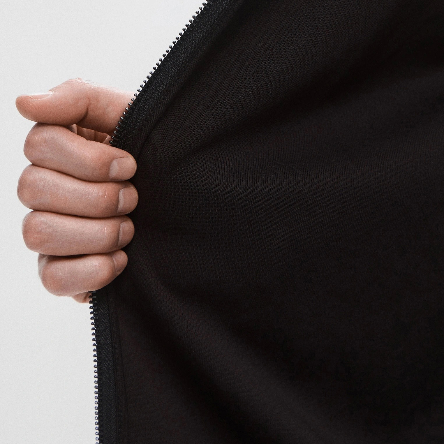 Mão segurando tecido preto com zipper