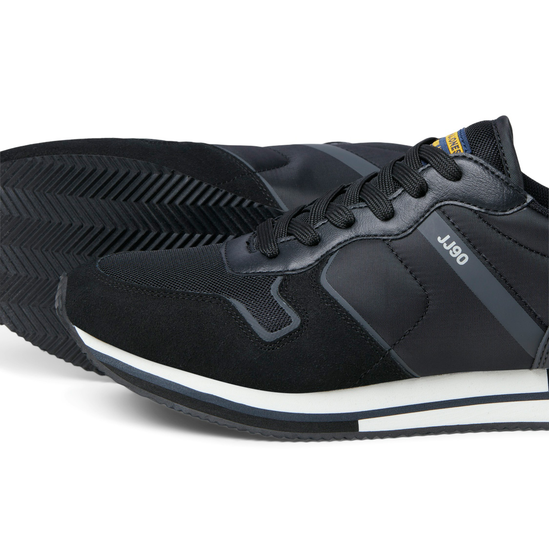 Ténis pretos com detalhes em cinzento e branco, inscrição JJ90 na lateral