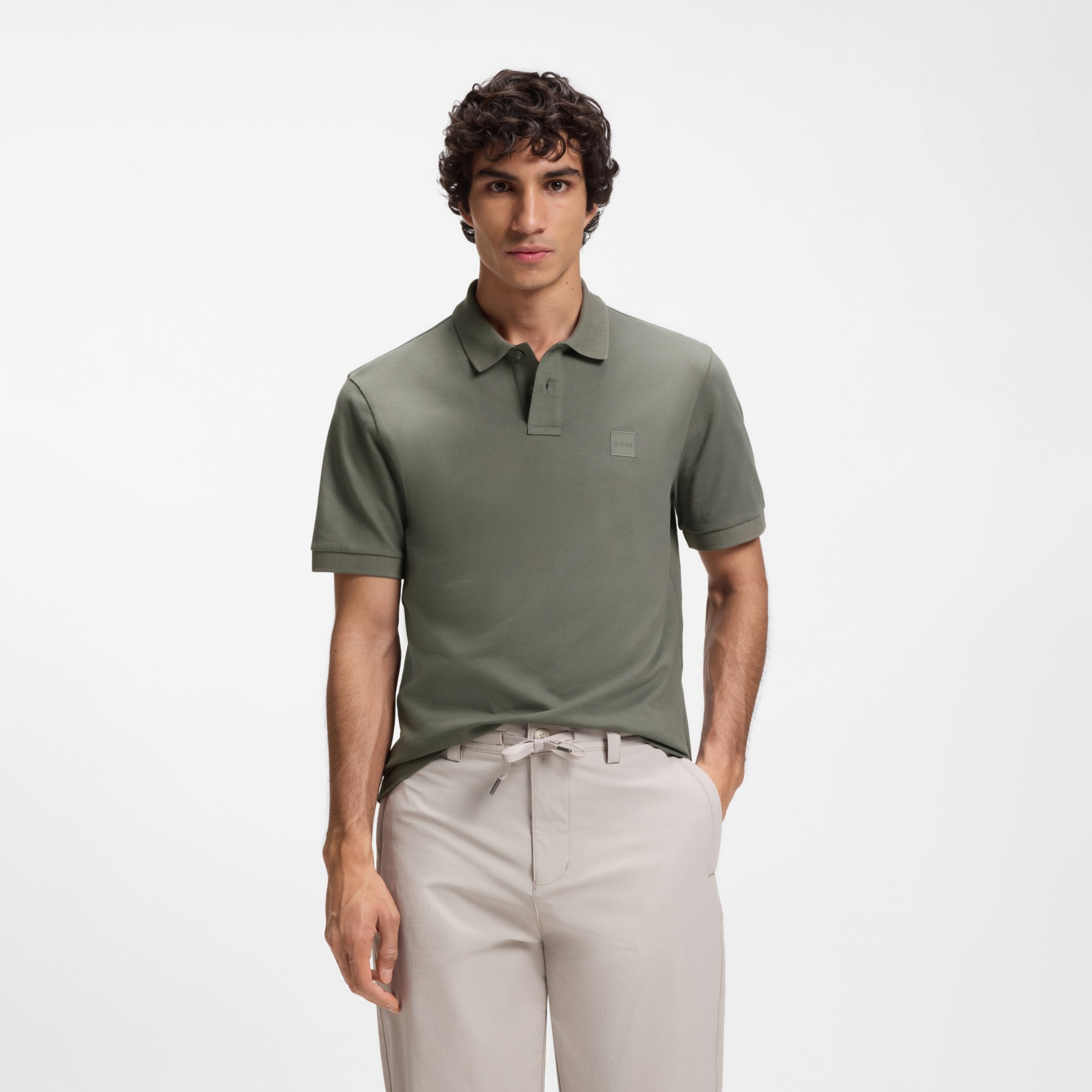Homem a usar camisola polo verde militar e calças claras