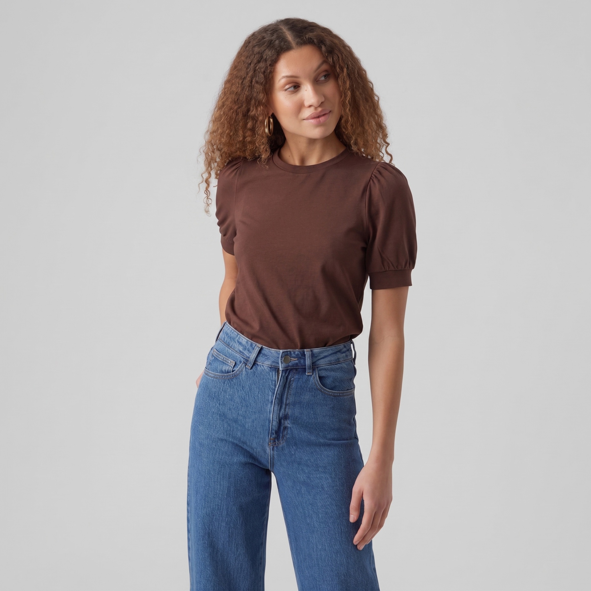 Mulher com t-shirt castanha e calças de ganga azul