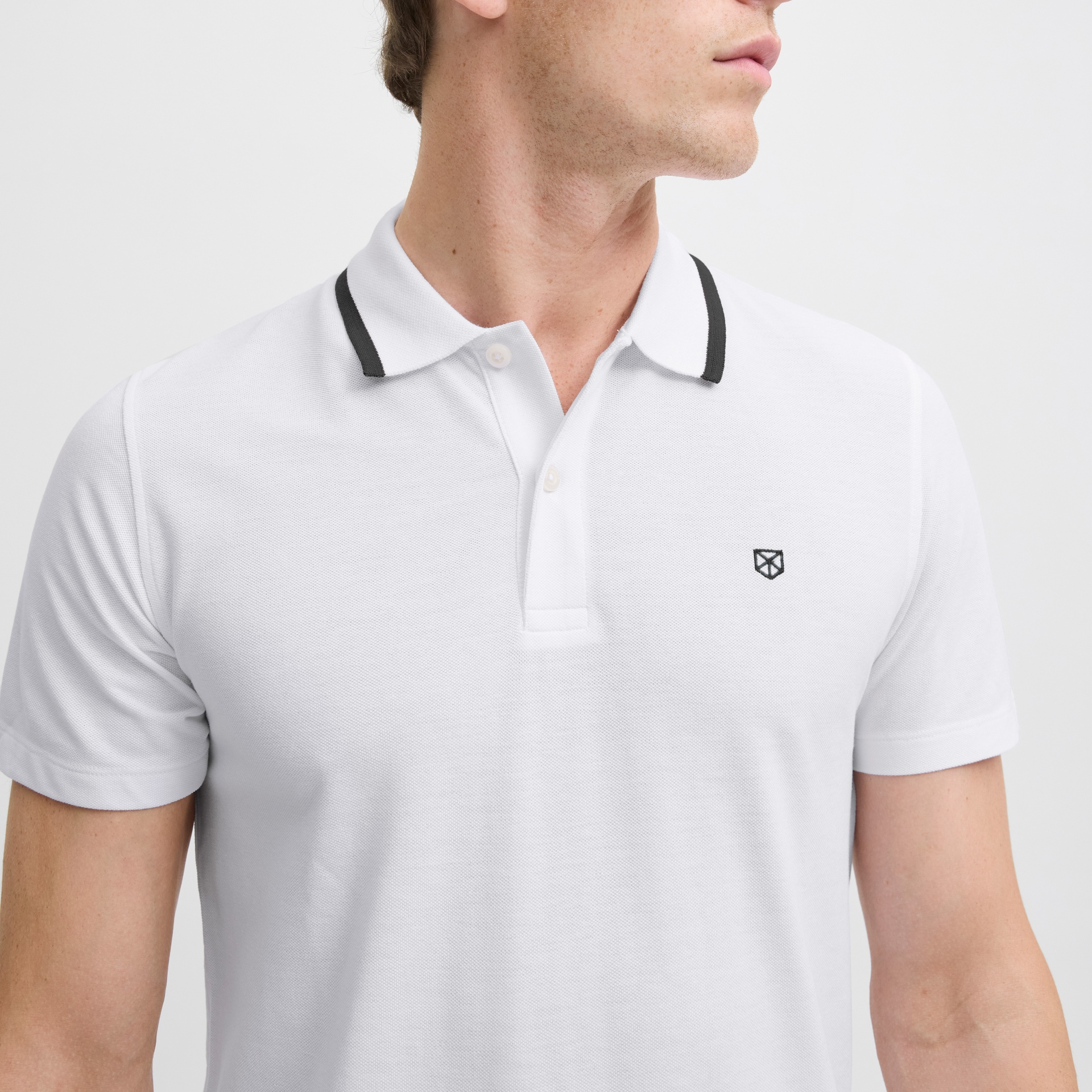 Polo branco de manga curta com gola preta e logótipo bordado no peito.