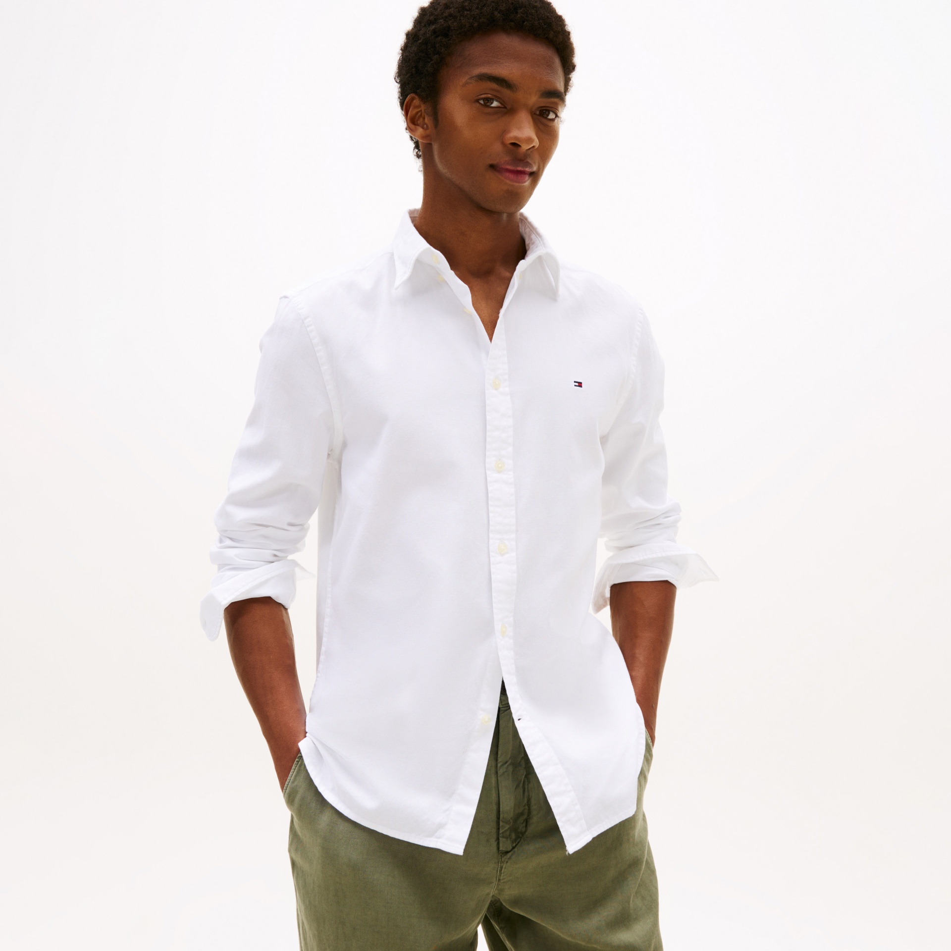 Camisa branca de algodão com logo bordado no peito usada por homem com calças verde-oliva.