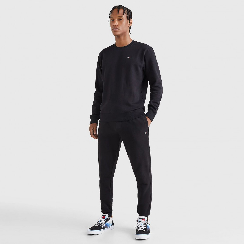 Homem com roupa desportiva preta e sapatilhas coloridas