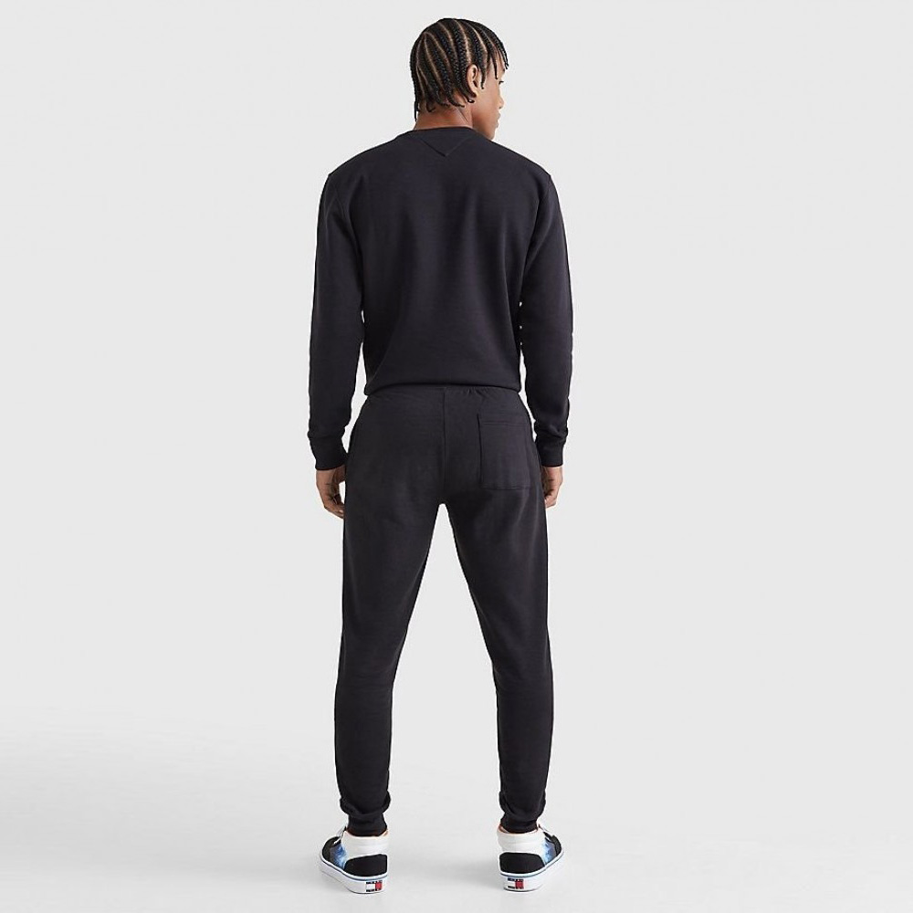 Homem de costas com conjunto desportivo preto e sapatilhas brancas com detalhes coloridos