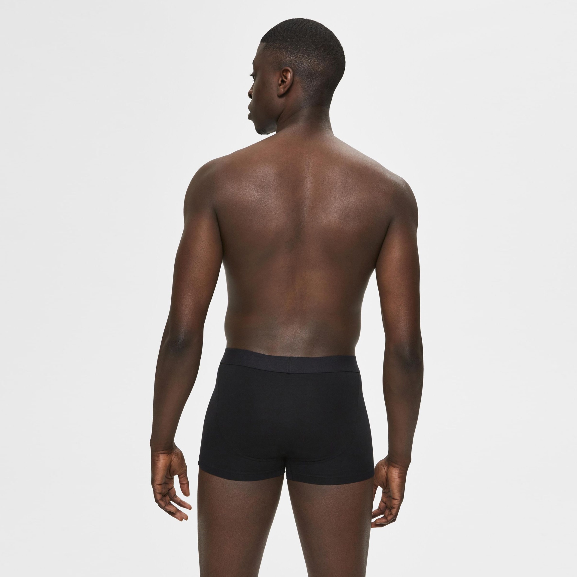 Homem de costas a usar boxers pretos lisos