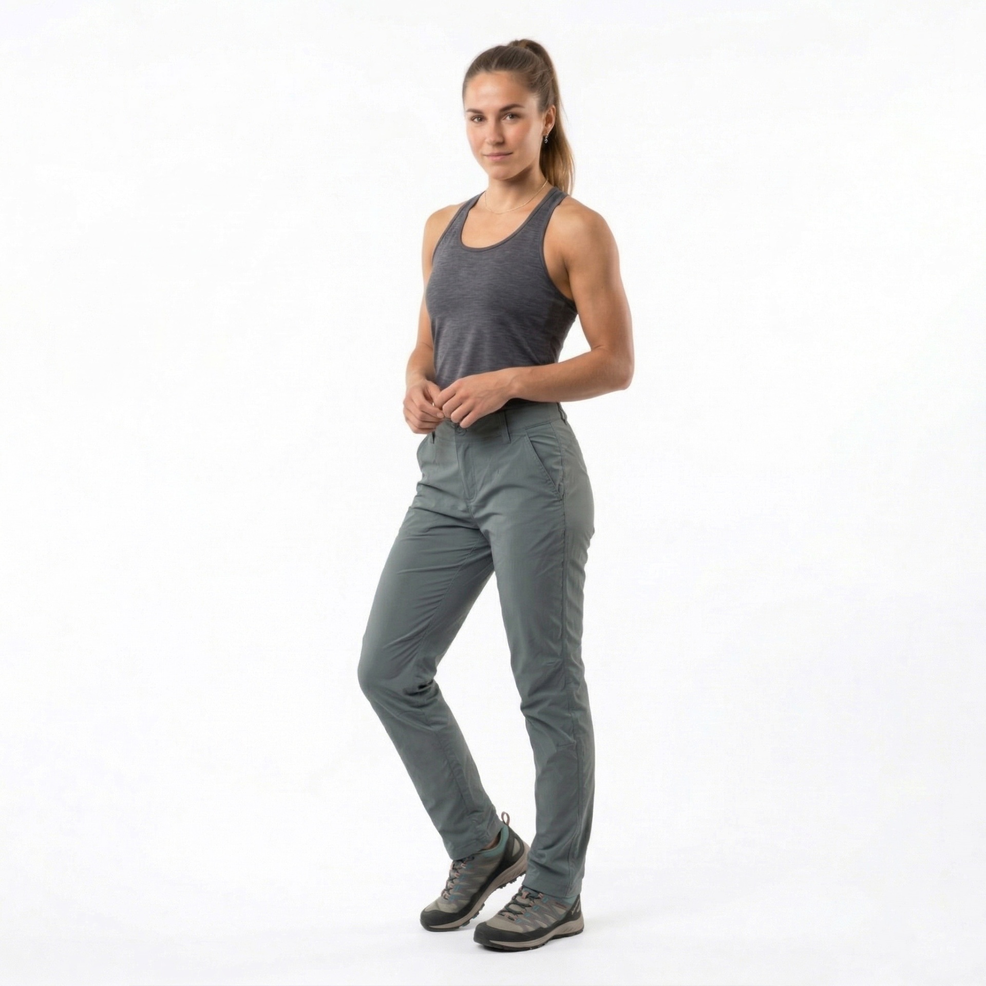 Mulher com camisola cinzenta e calças de trekking cinza-esverdeadas e botas cinzentas