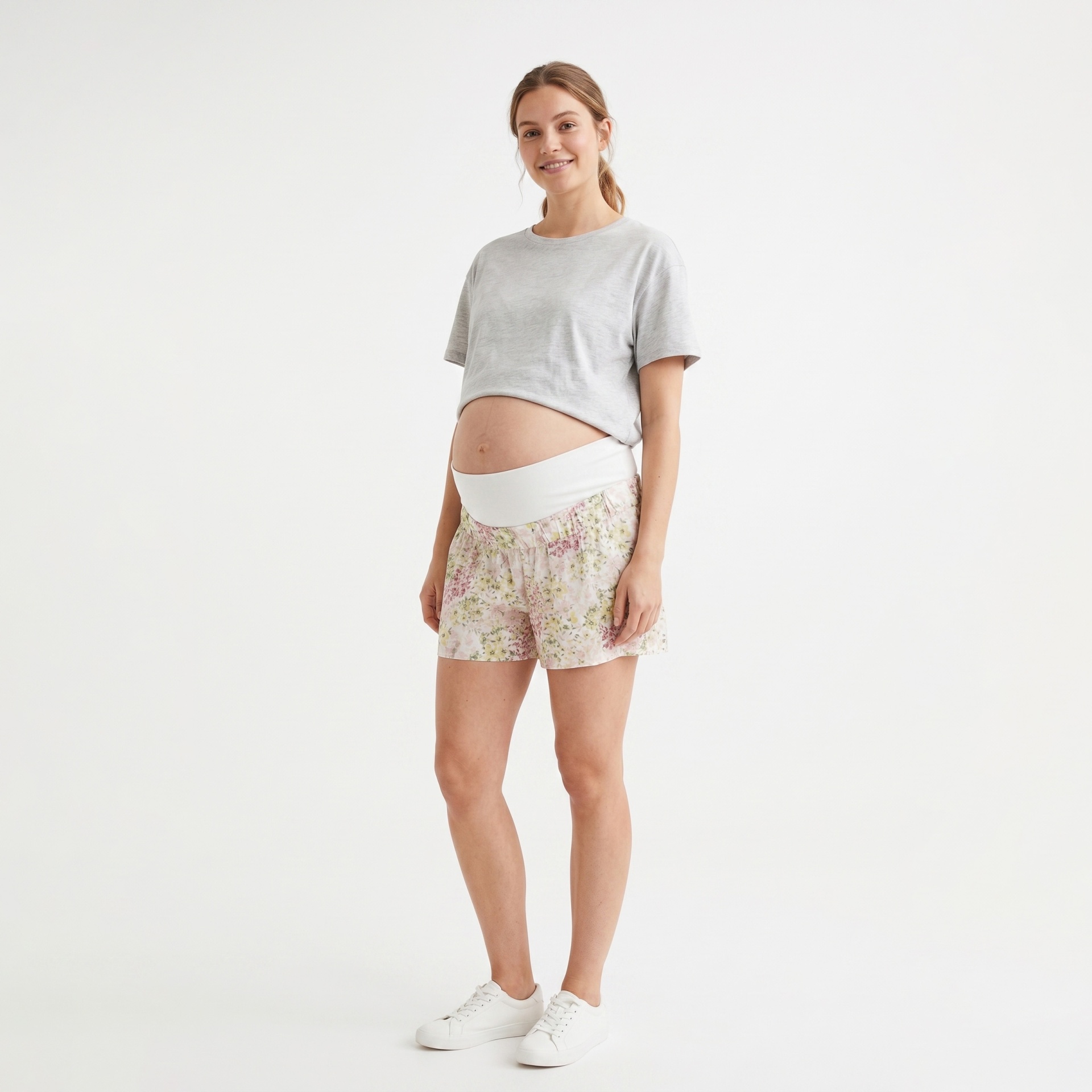 Mulher grávida posa com roupa casual de maternidade em fundo branco