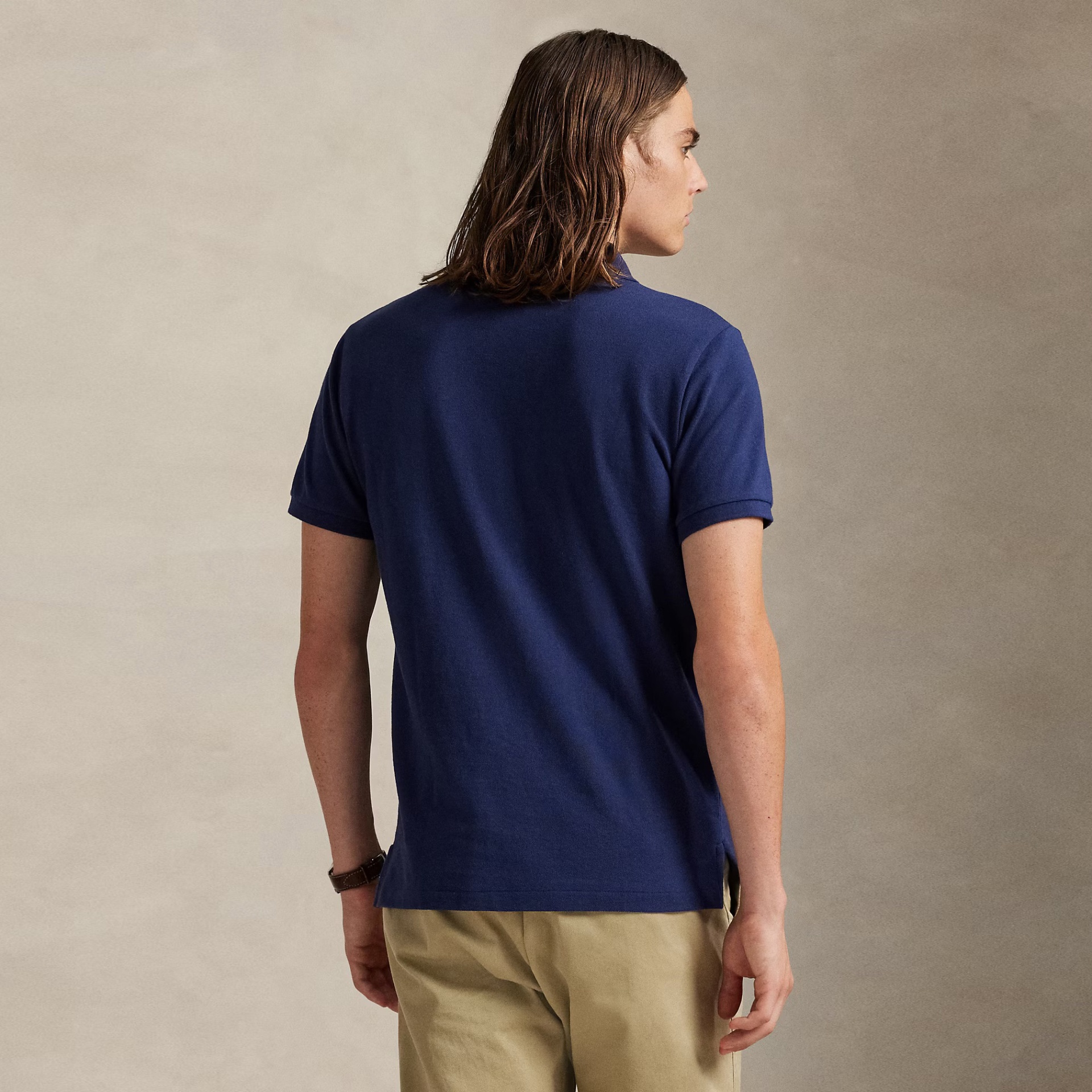 Pessoa de costas com camisa polo azul e calças beges