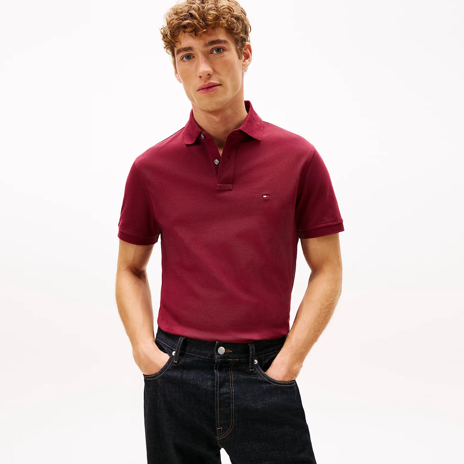 Homem com polo bordô de manga curta e calças de ganga escuras