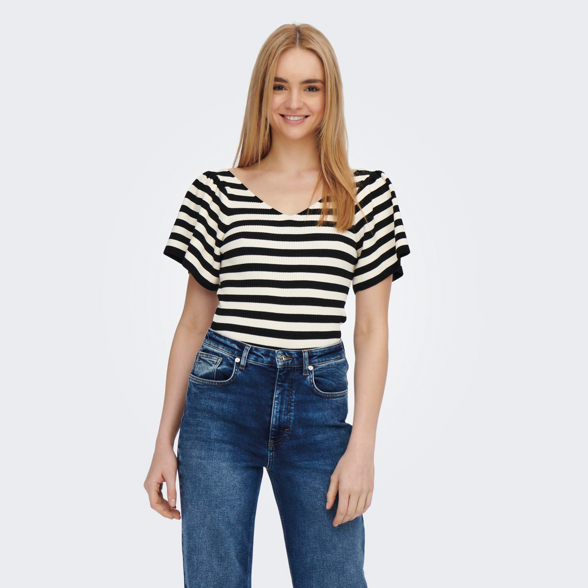 Mulher com camisa às riscas preta e branca e calças de ganga azuis