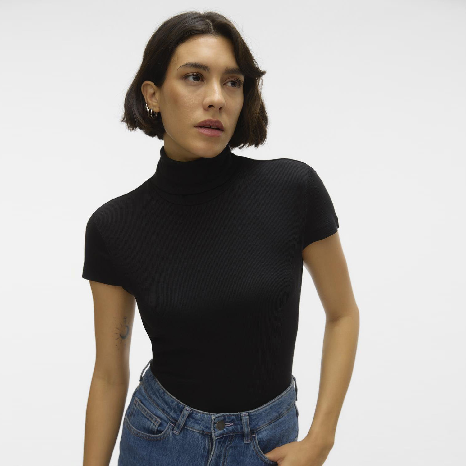 Mulher com t-shirt preta de gola alta e manga curta e jeans azuis