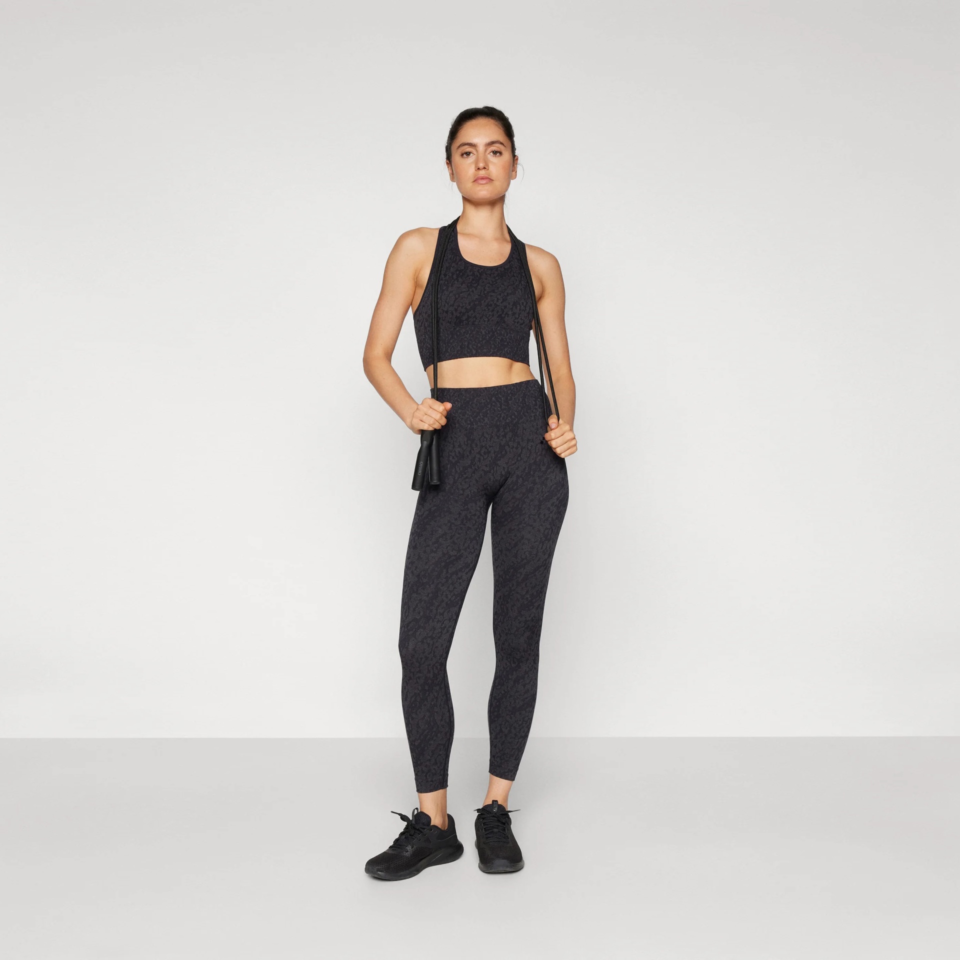 Roupa desportiva feminina preta com padrão discreto em fundo branco