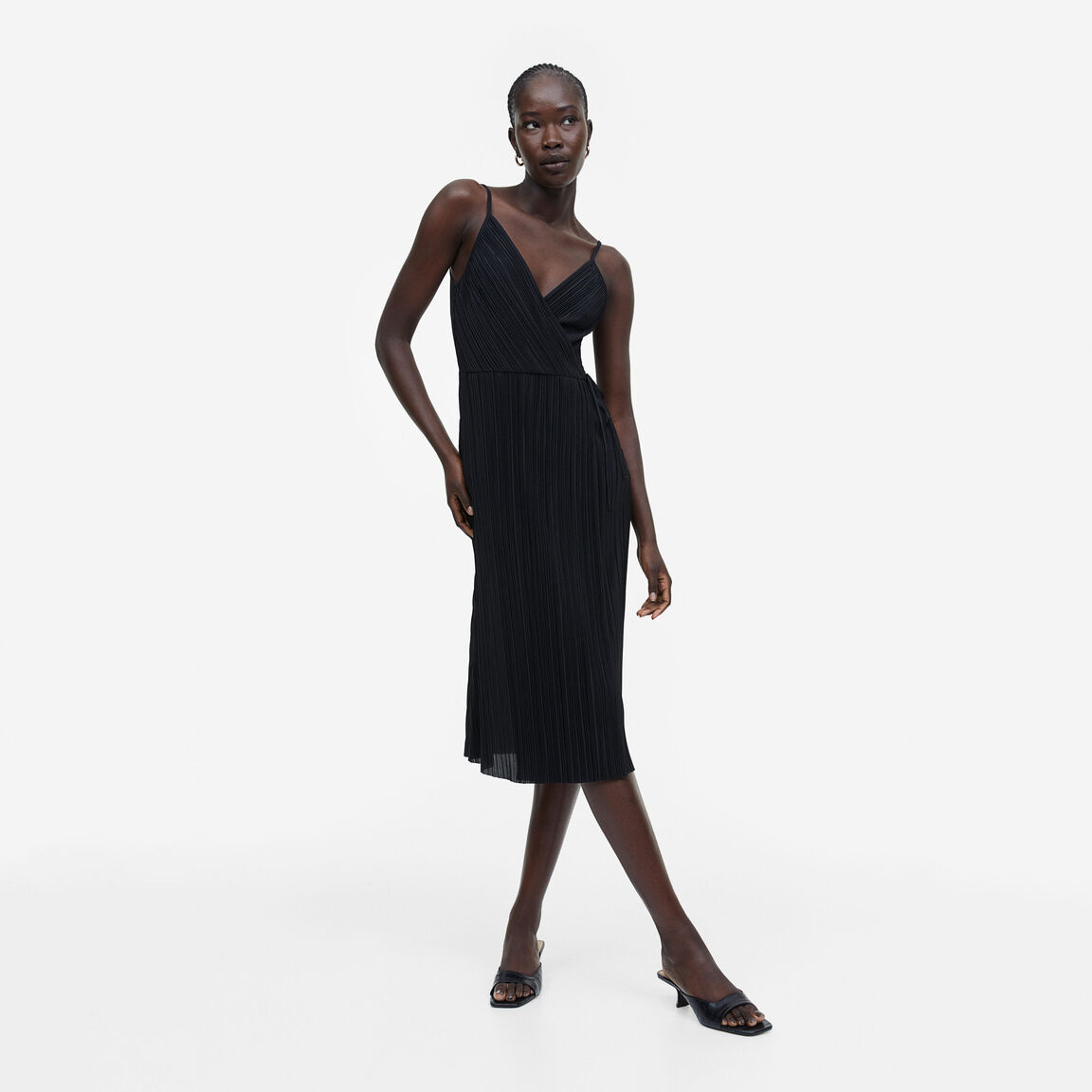 Vestido midi preto pregueado com alças finas e sandálias de salto.
