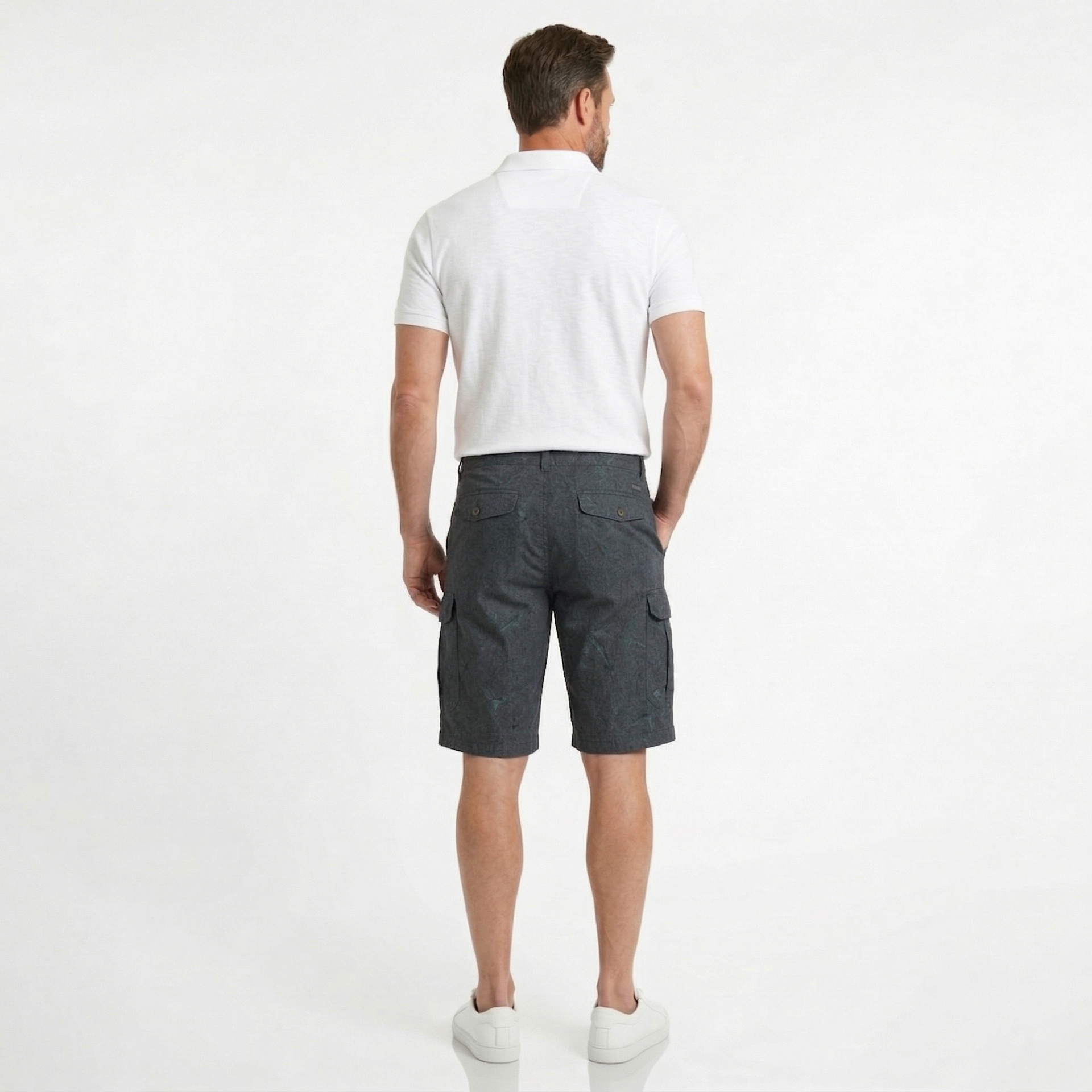 Homem visto de costas com calções cargo cinza escuro e polo branca