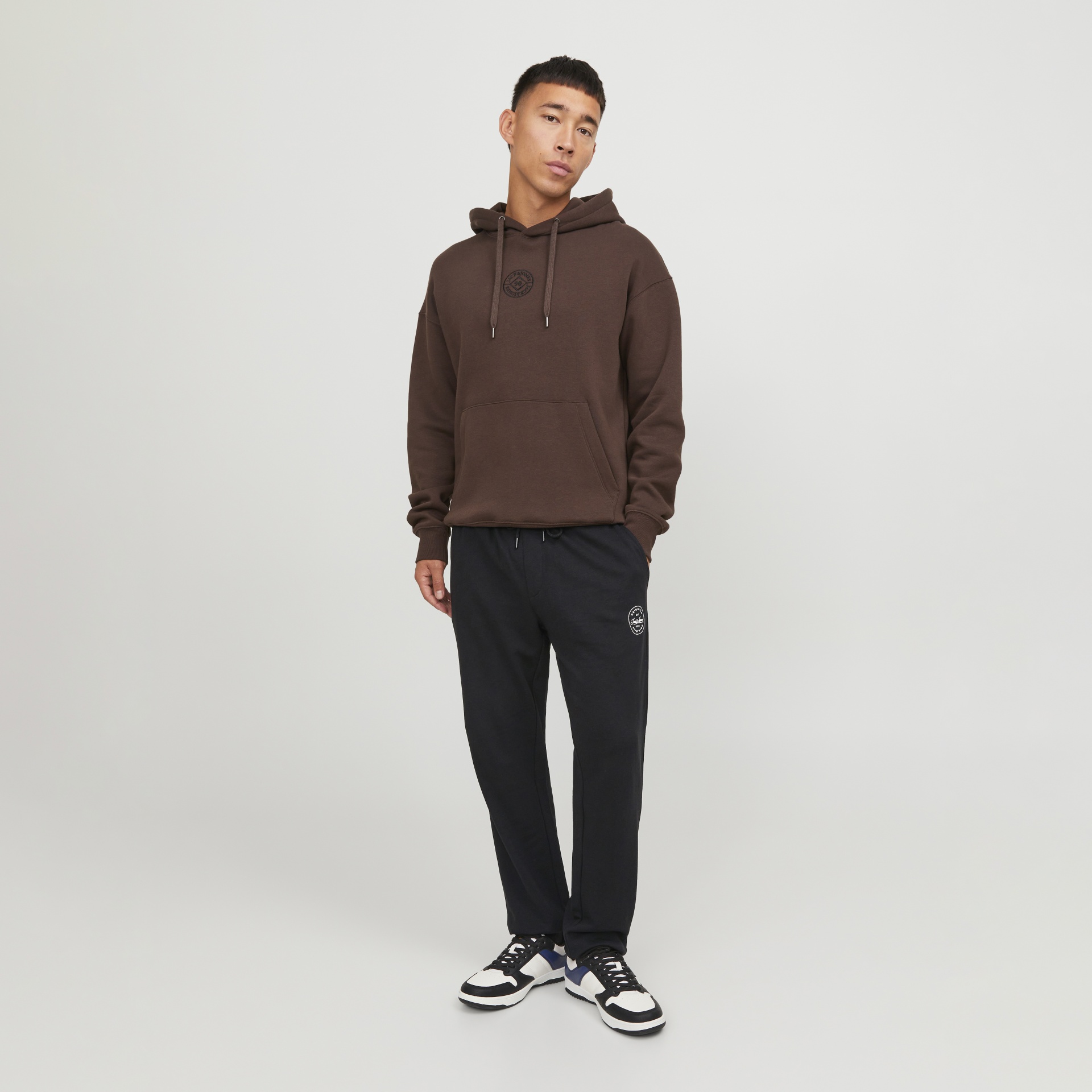 Homem com sweatshirt castanha e calças pretas com sapatilhas desportivas