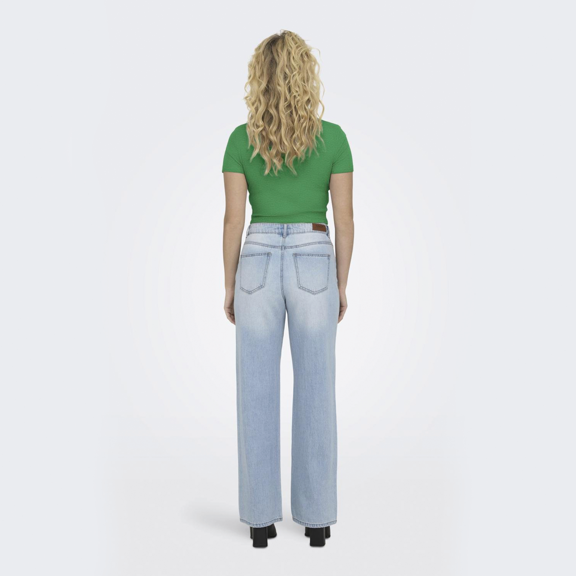 Mulher de costas com t-shirt verde e jeans azuis