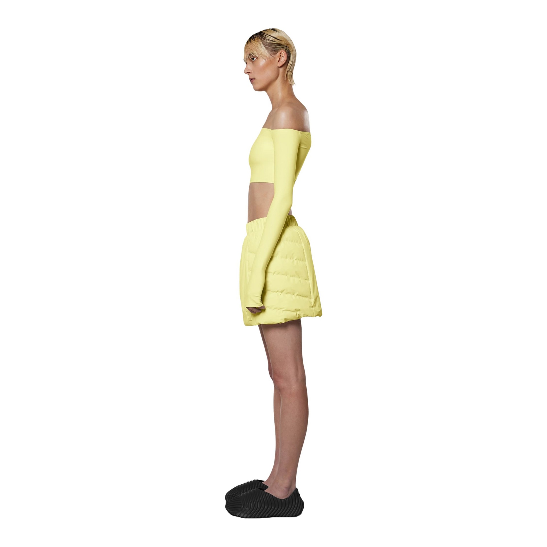 Pessoa a usar top crop amarelo manga longa, saia/shorts almofadados amarelos e ténis escuros estriados